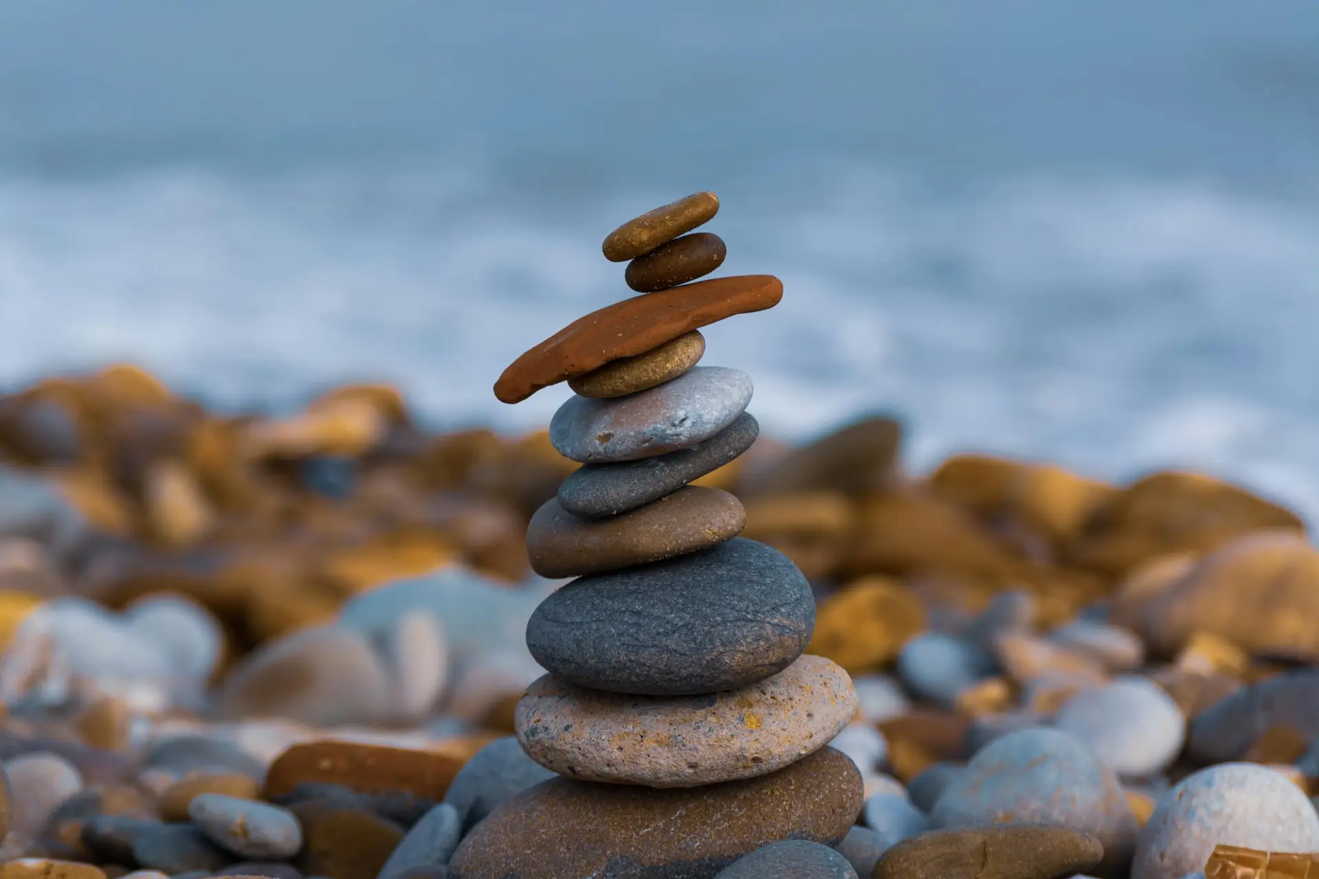 Close-up of a balanced stack of stones on a rocky beach, promoting serenity and zen.