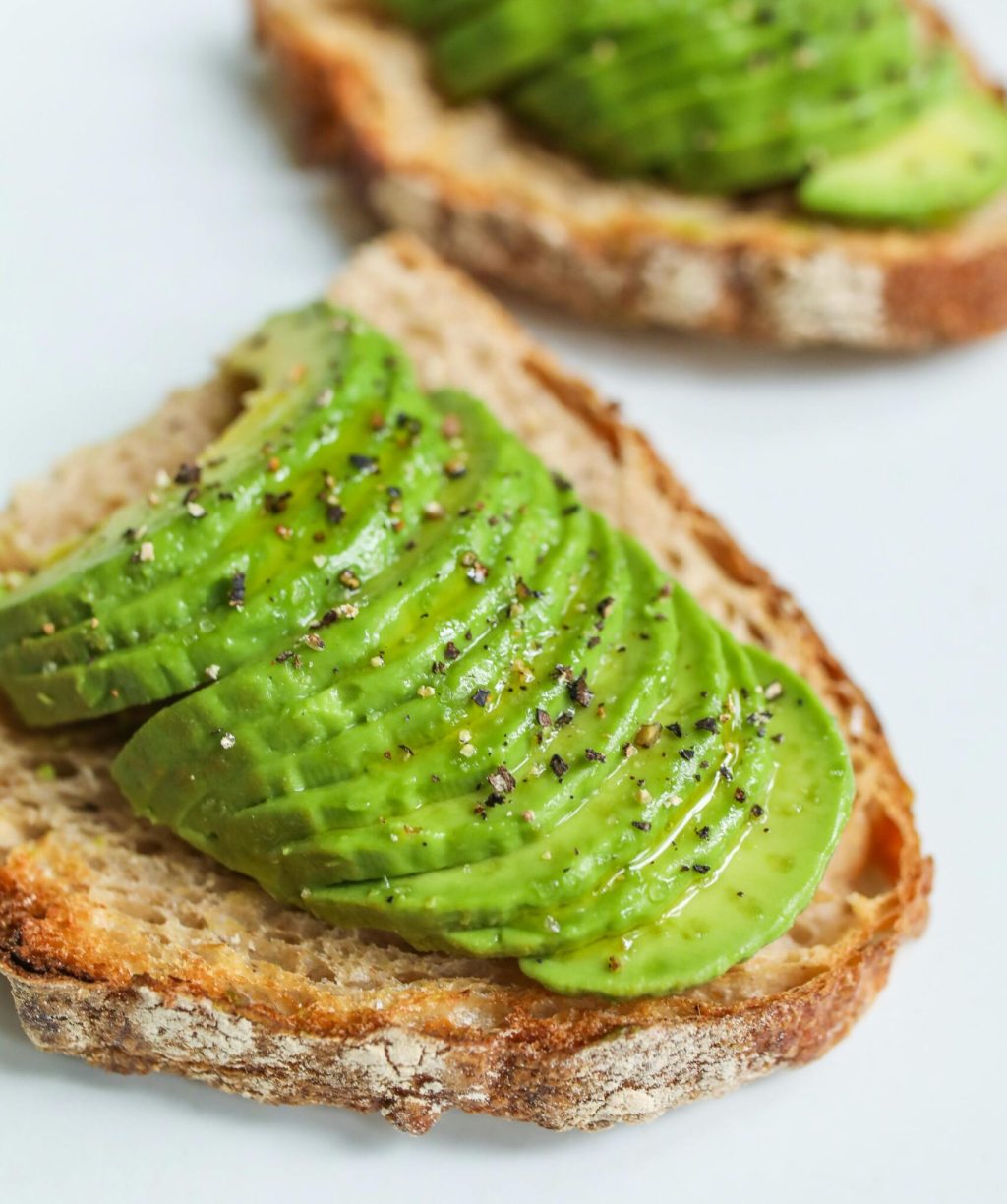 Sliced avocado atop sourdough bread, seasoned with pepper, photographed for a food photography series.