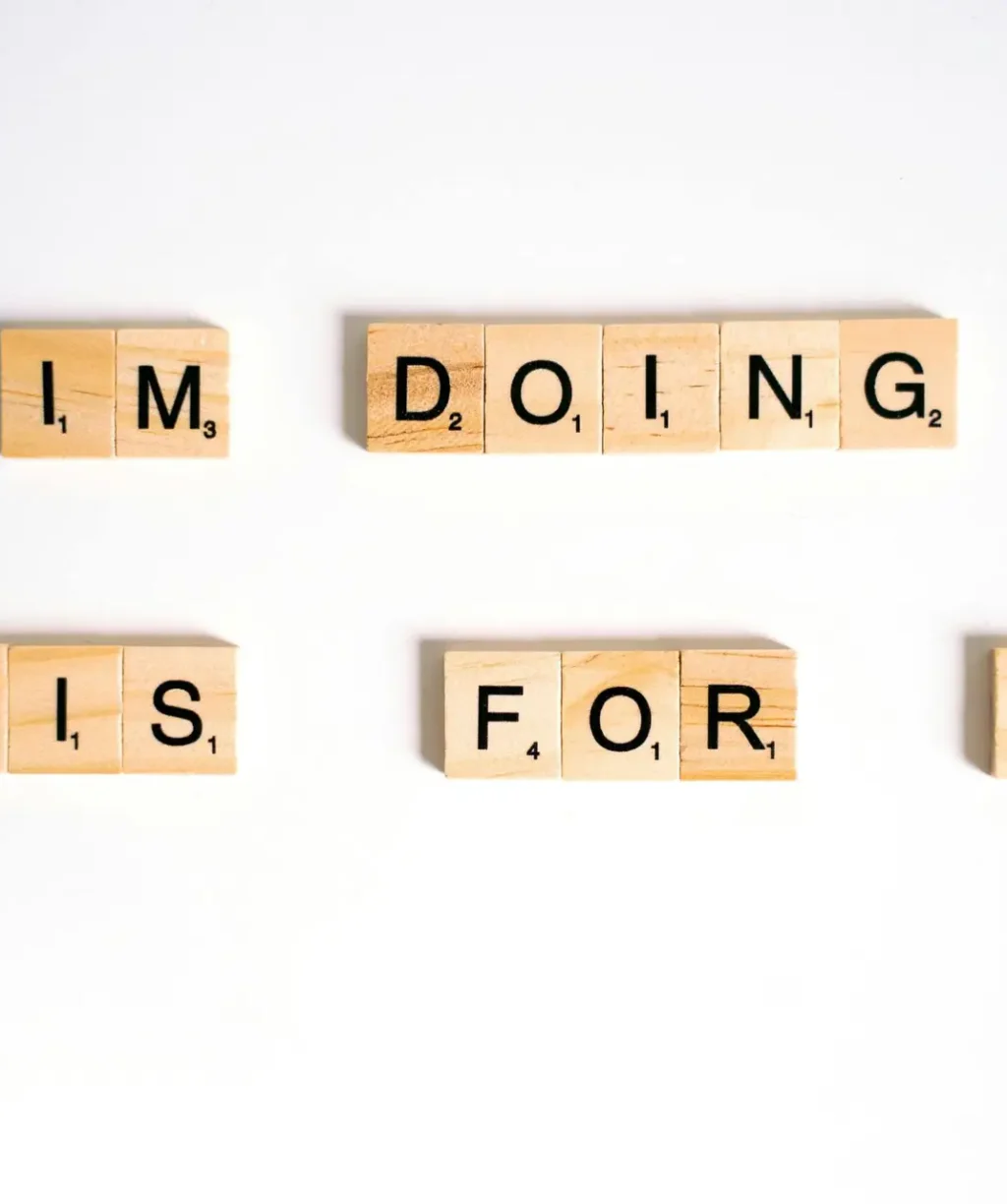 Wooden Scrabble tiles spell 'I'm doing this for me' on a white surface.